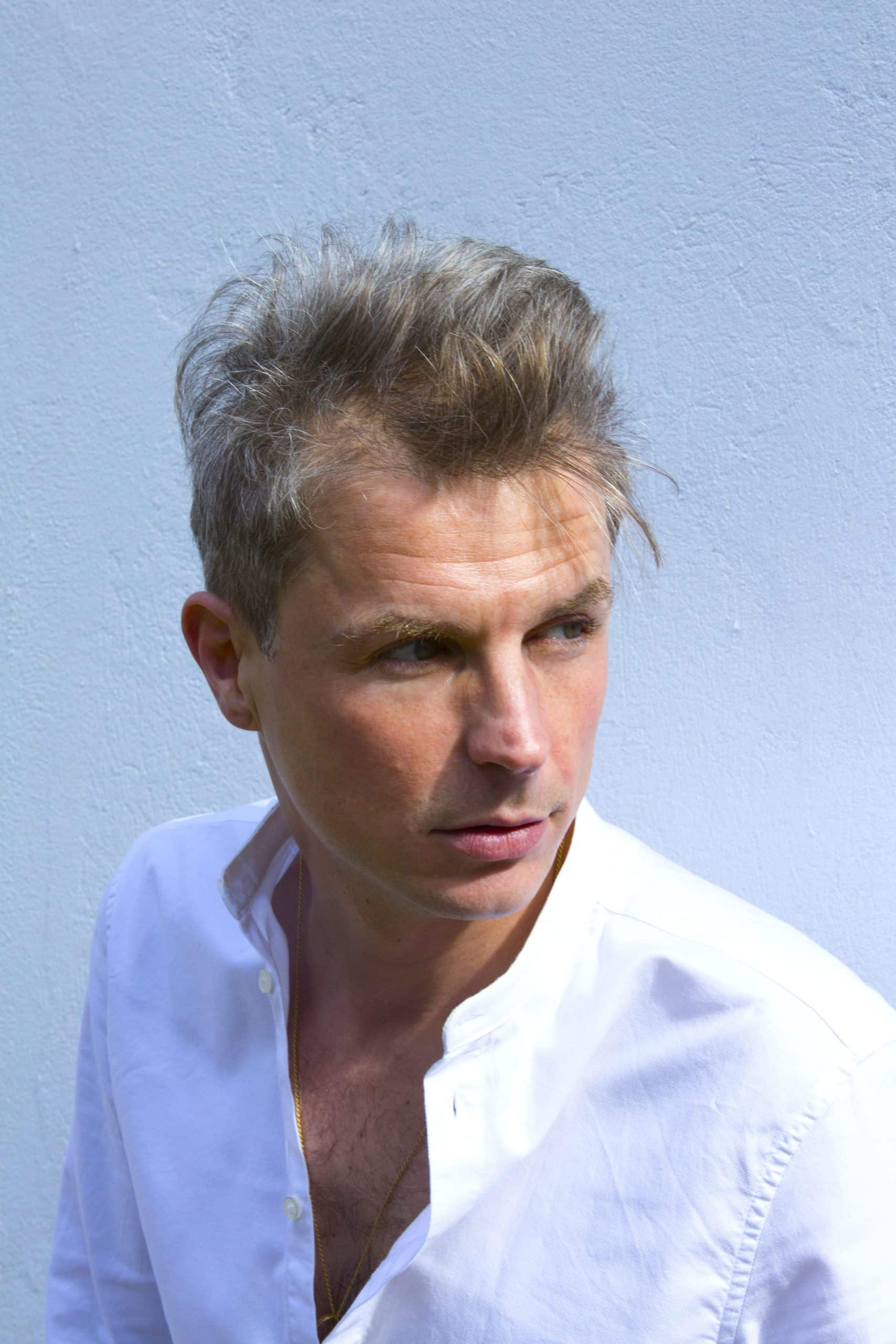 Oskar Salcedo con camisa blanca y fondo azul